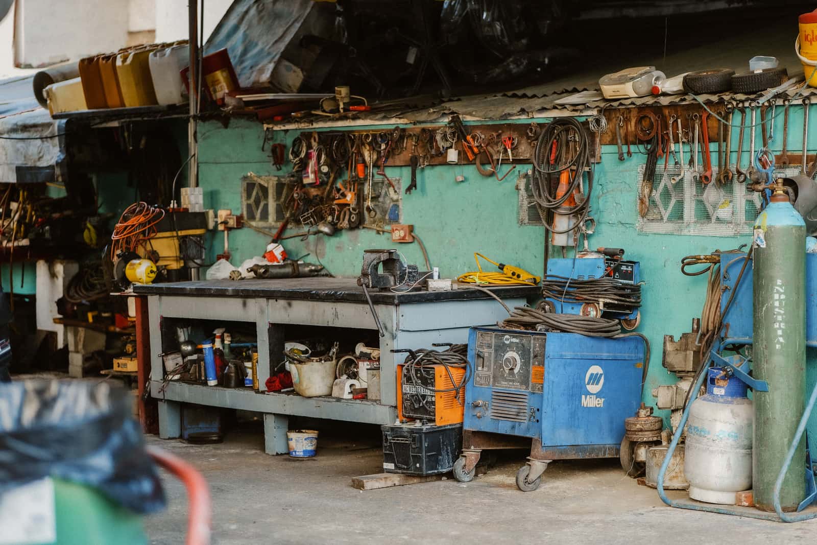 A compact workshop with tools, welding equipment and wall storage