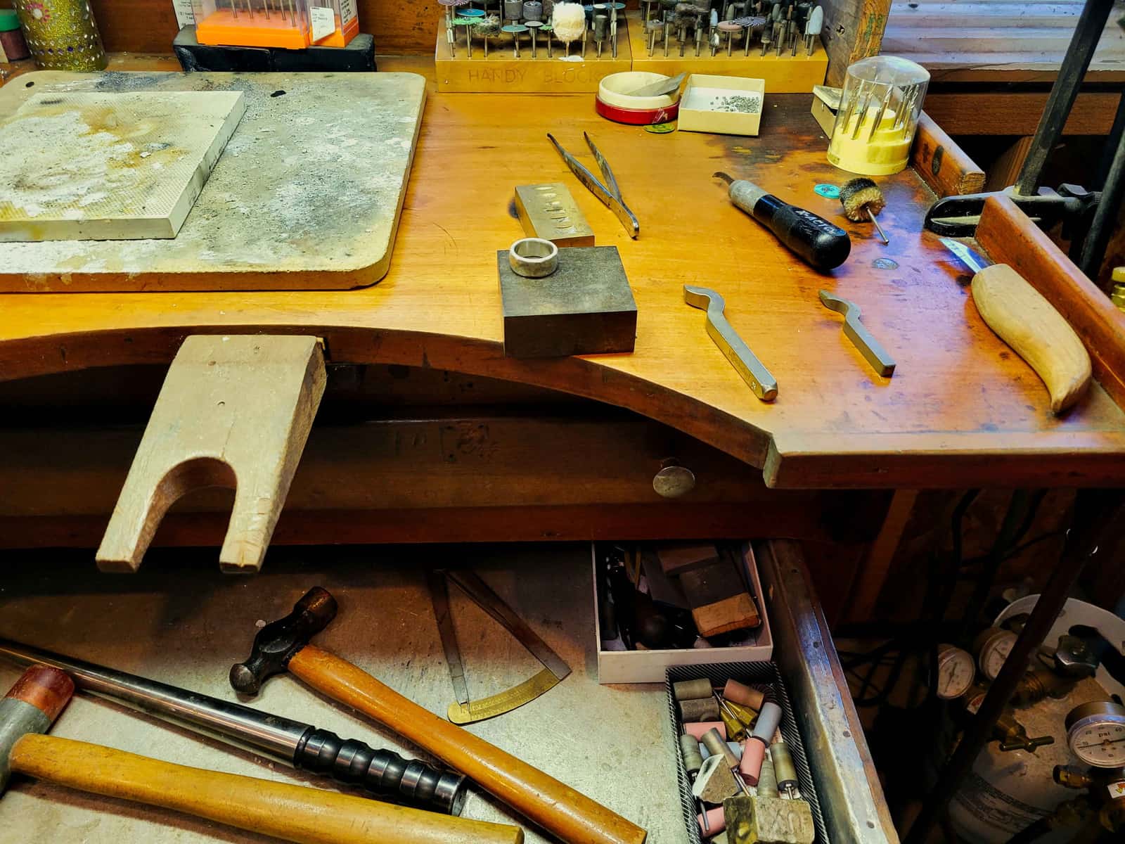 A workbench covered with hand tools and materials under natural light