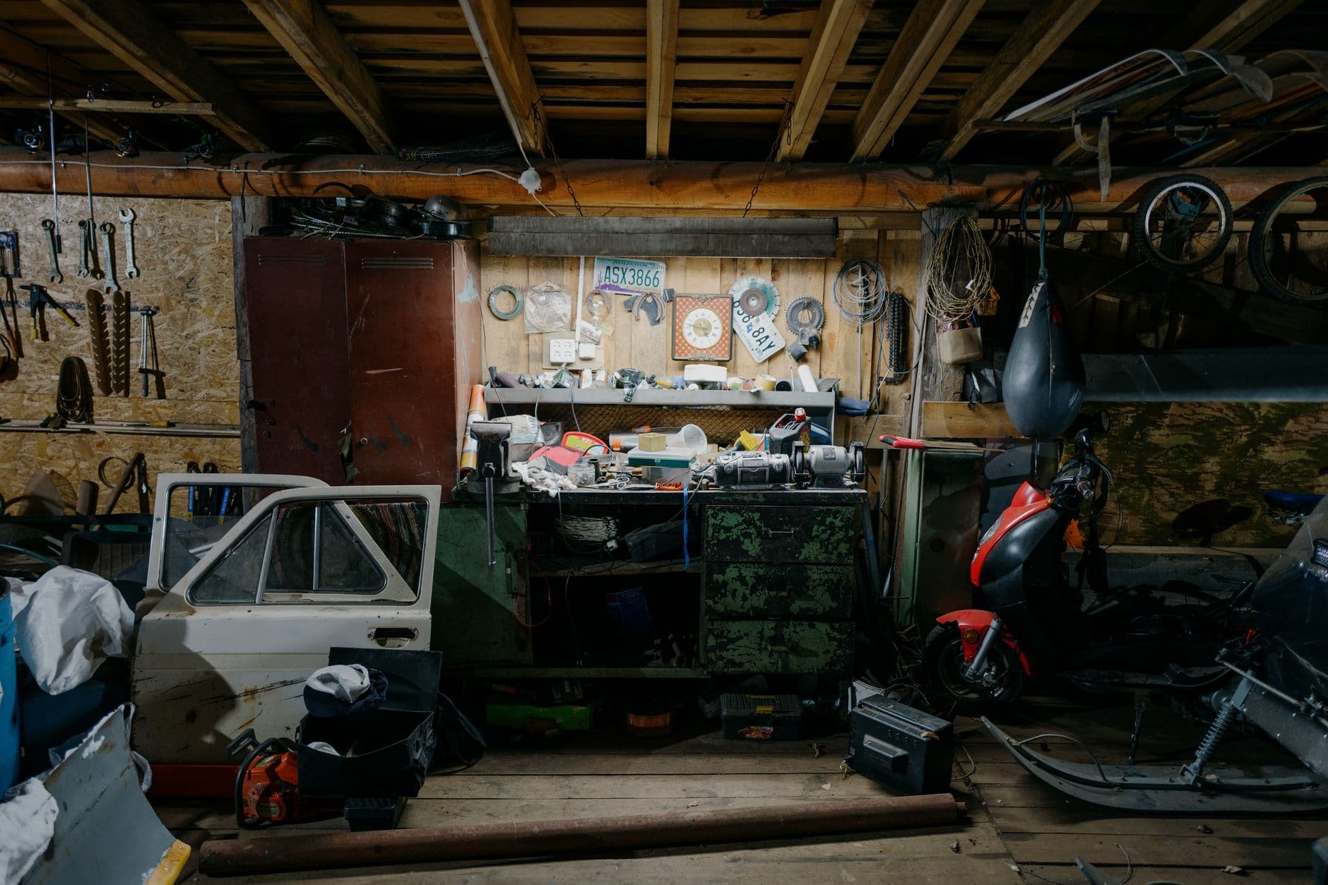 A working garage interior with tools, a motorcycle and parts on the floor