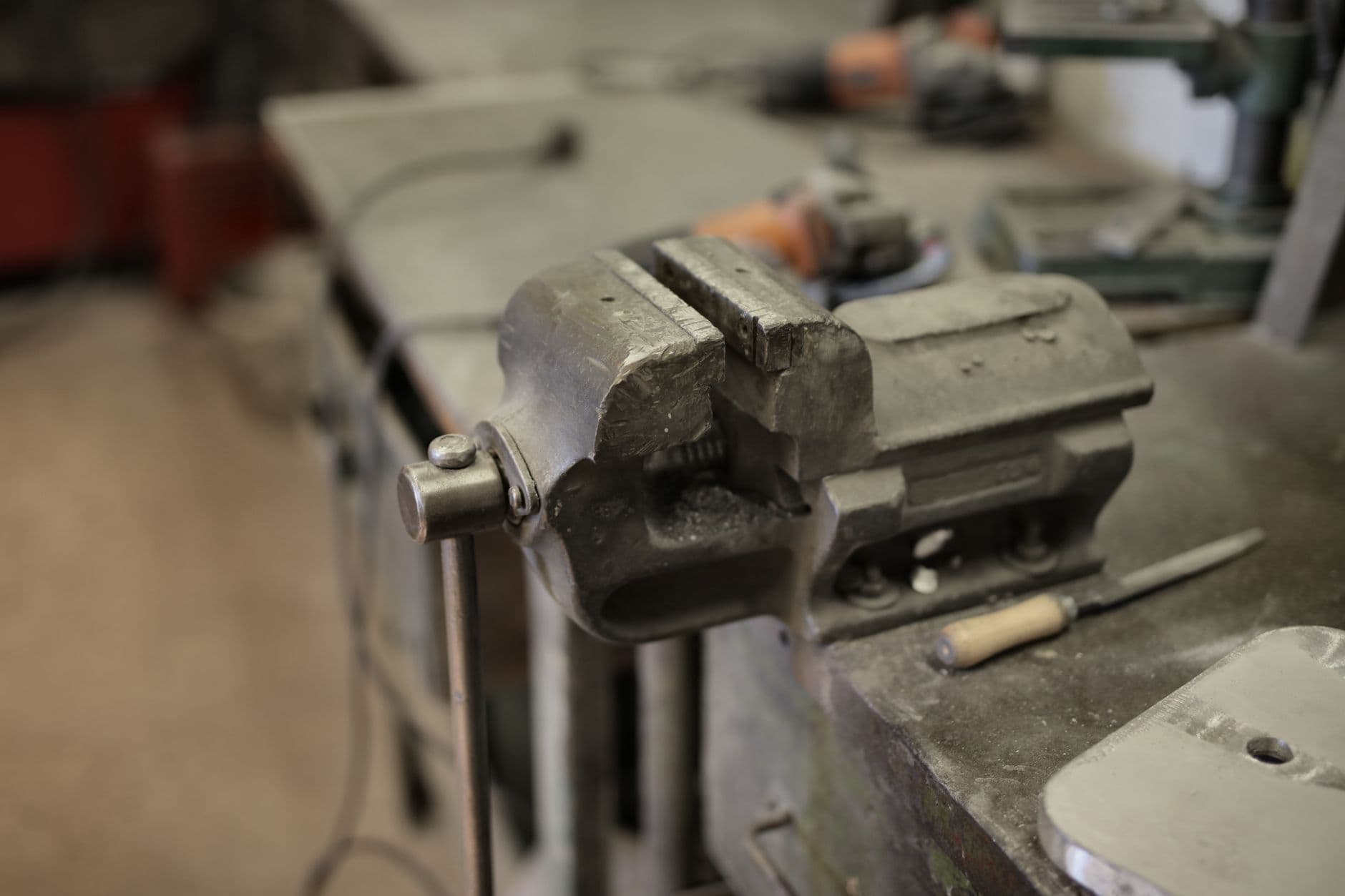 A vise fixed to a workbench surrounded by hand tools, seen from above