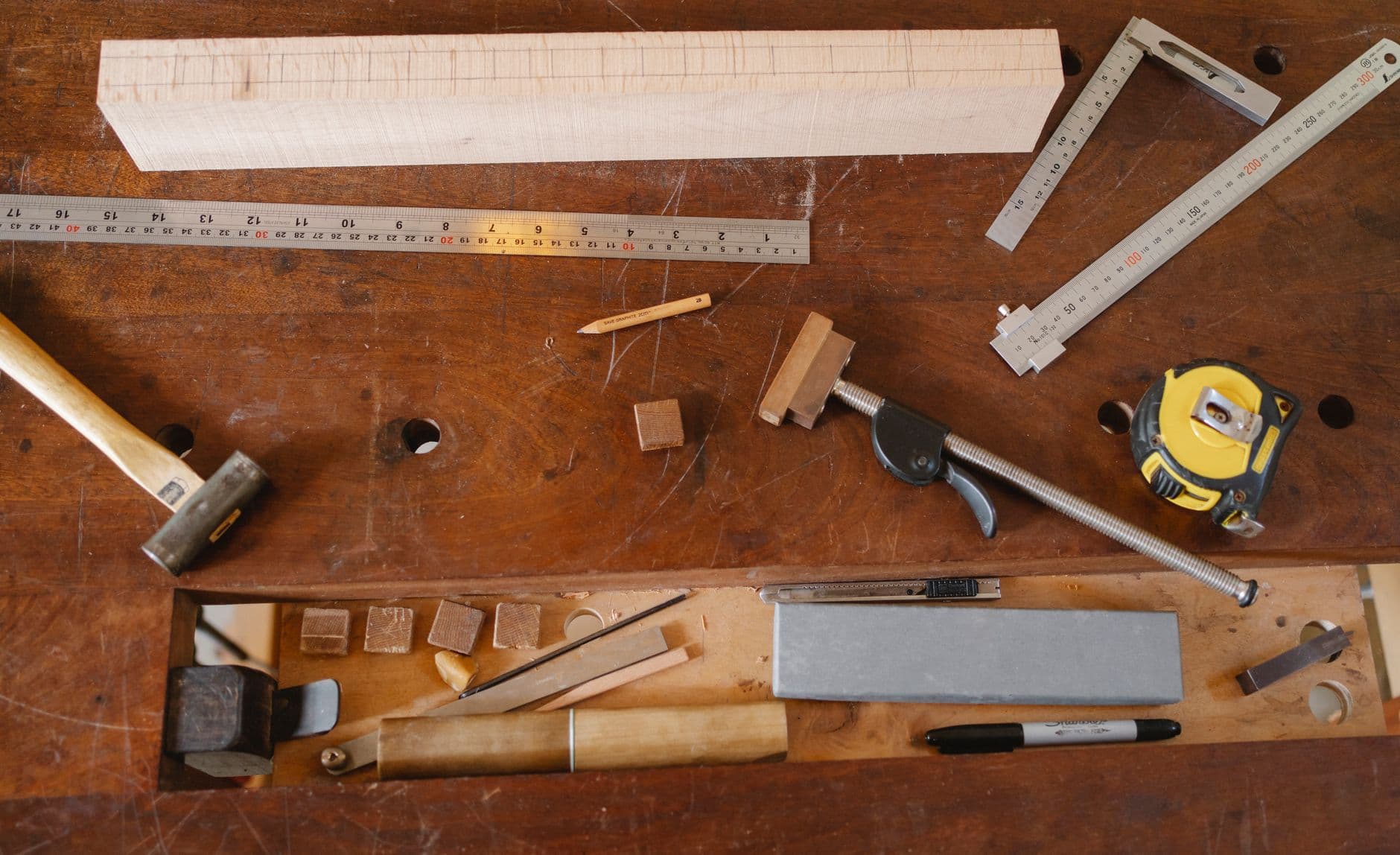 Joinery and measuring tools laid out on a timber table, seen from above