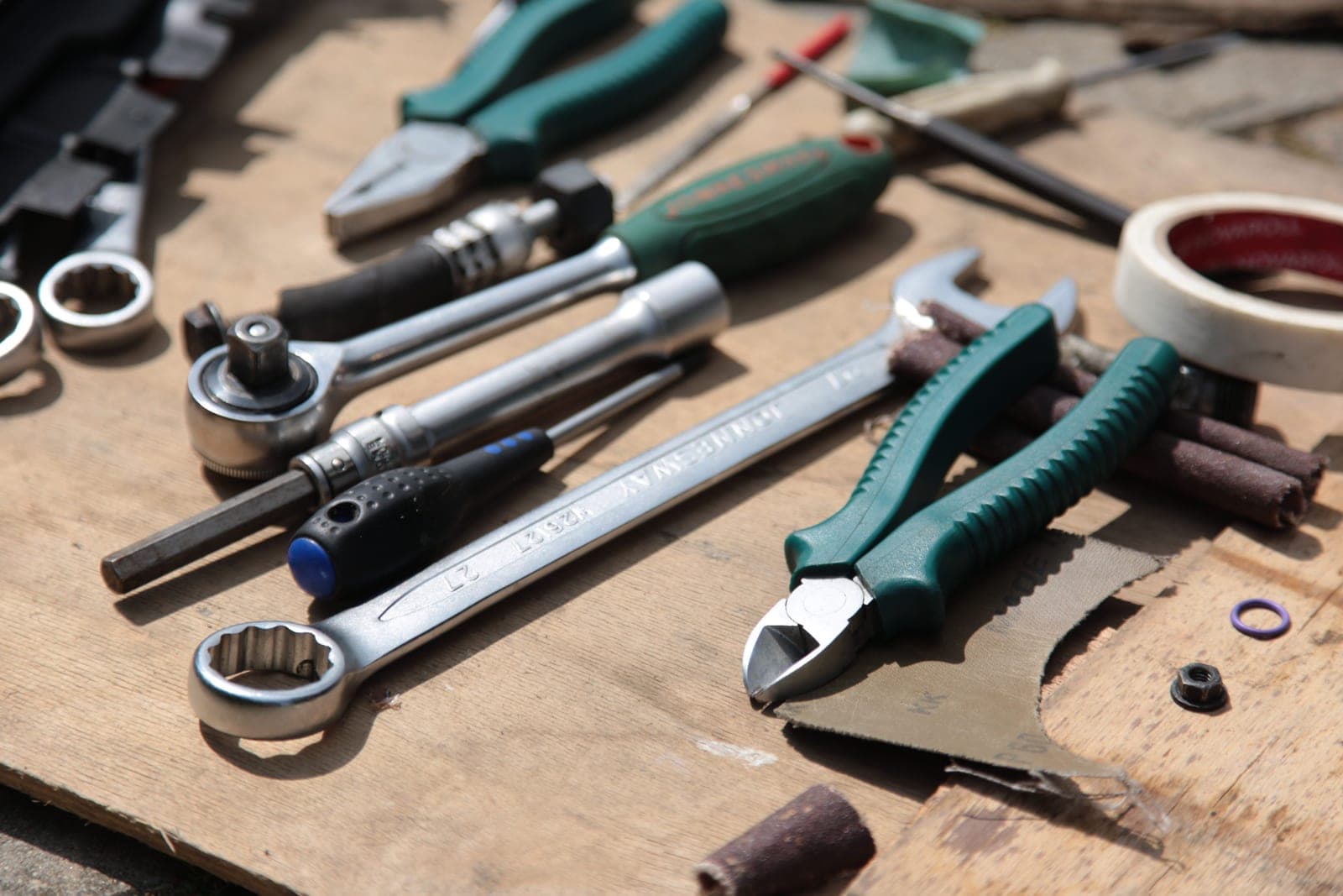 Pliers and a wrench resting on a wooden bench top