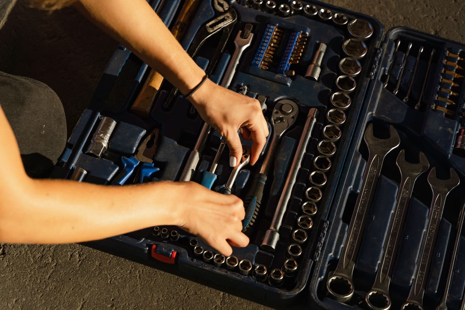 Hands sorting tools into a toolbox, photographed from above in natural light