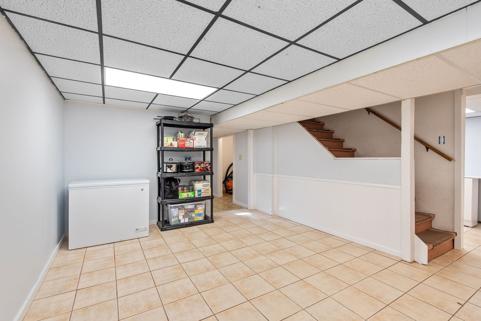 A basement storage area with metal storage shelves along a tiled floor