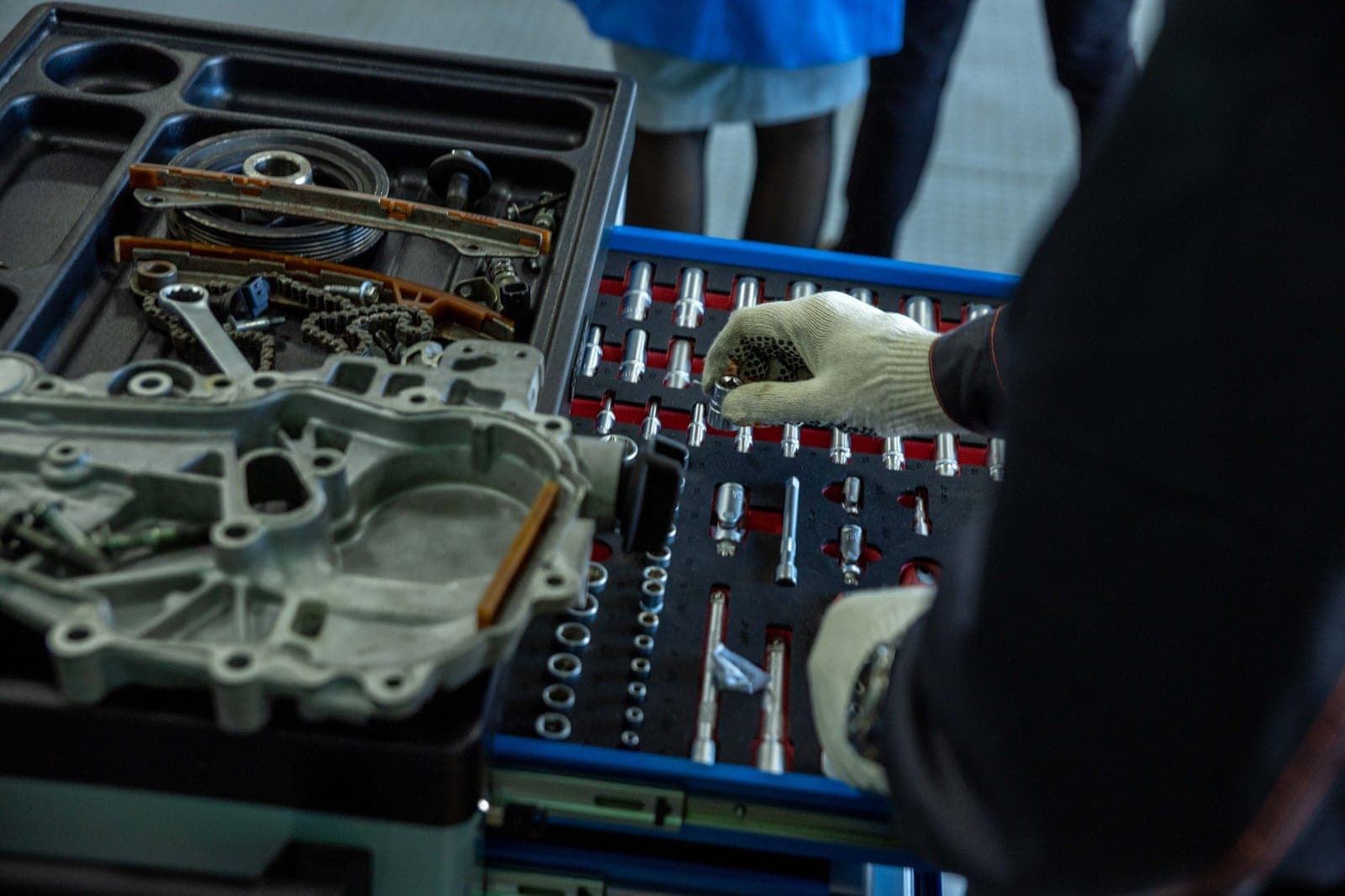 A mechanic in gloves sorting parts and tools in a workshop