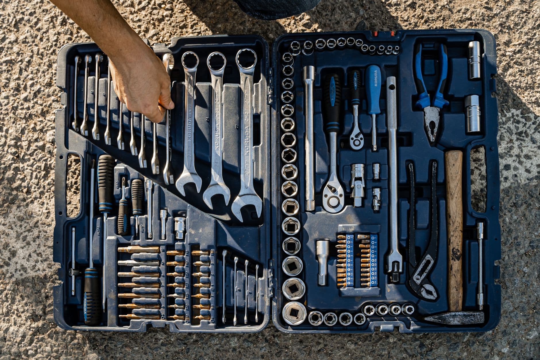 An open toolkit with assorted wrenches and pliers photographed outdoors