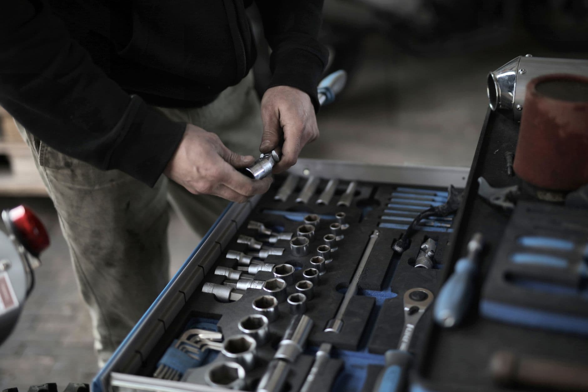 A mechanic selecting tools from a comprehensive toolset in a workshop