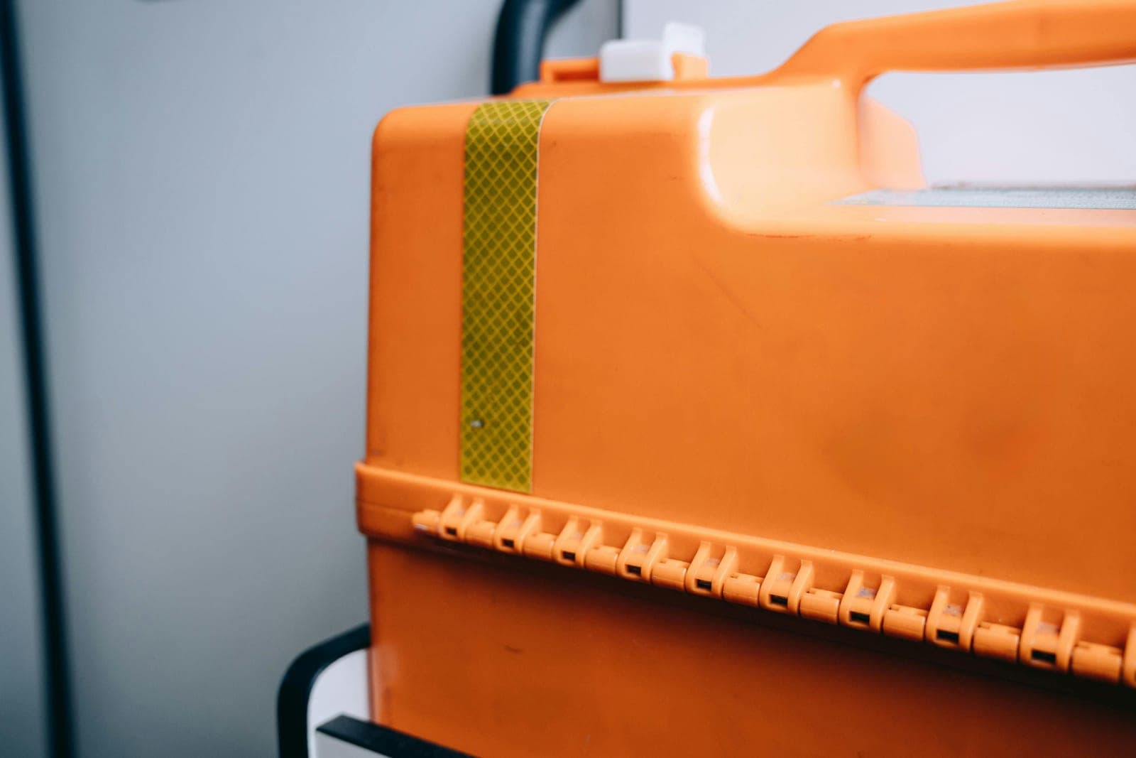 An orange portable tool box photographed against a blurred background