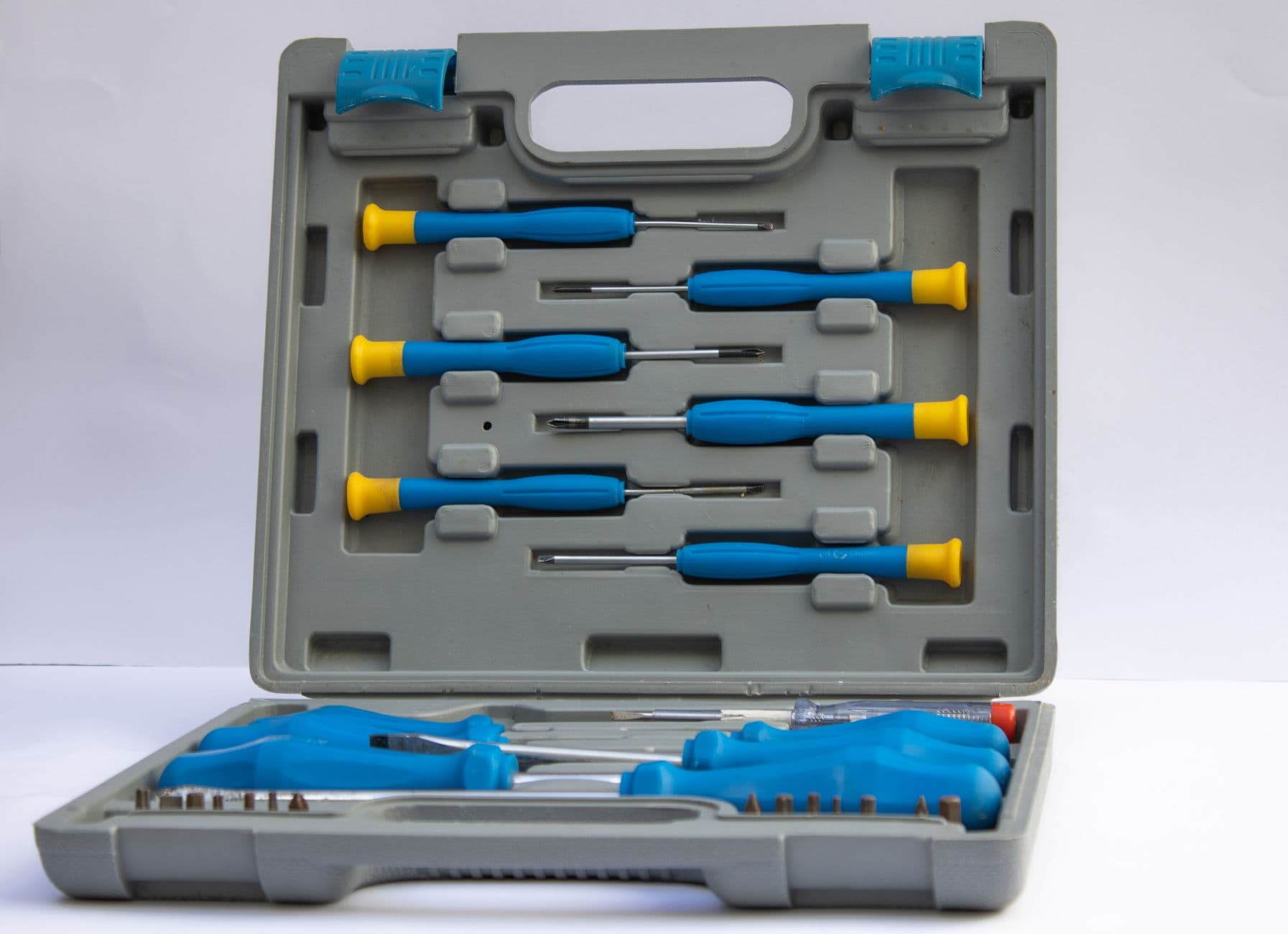An open gray plastic toolbox holding a set of screwdrivers with blue handles