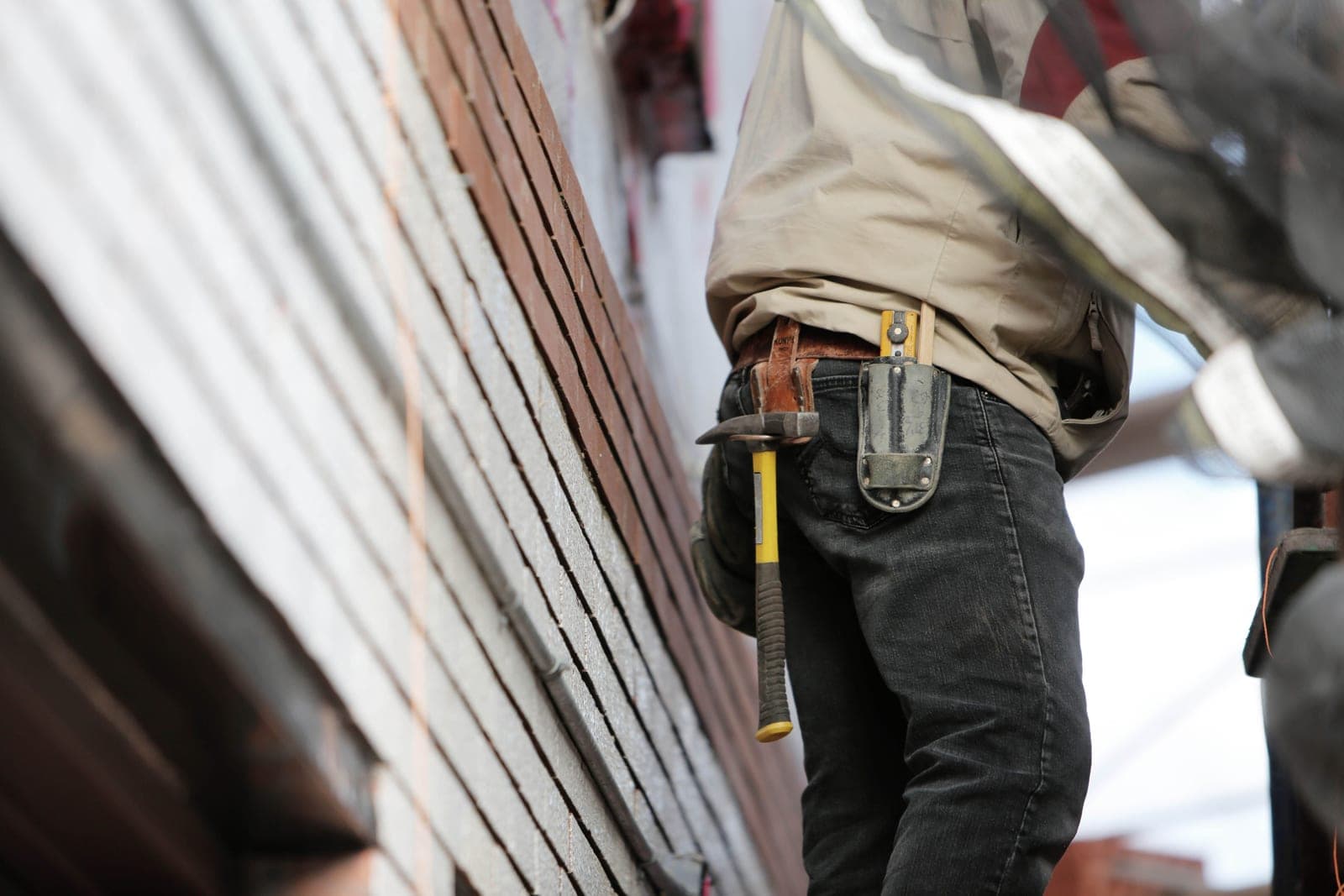 A worker holding a hammer beside a set of tools on a job