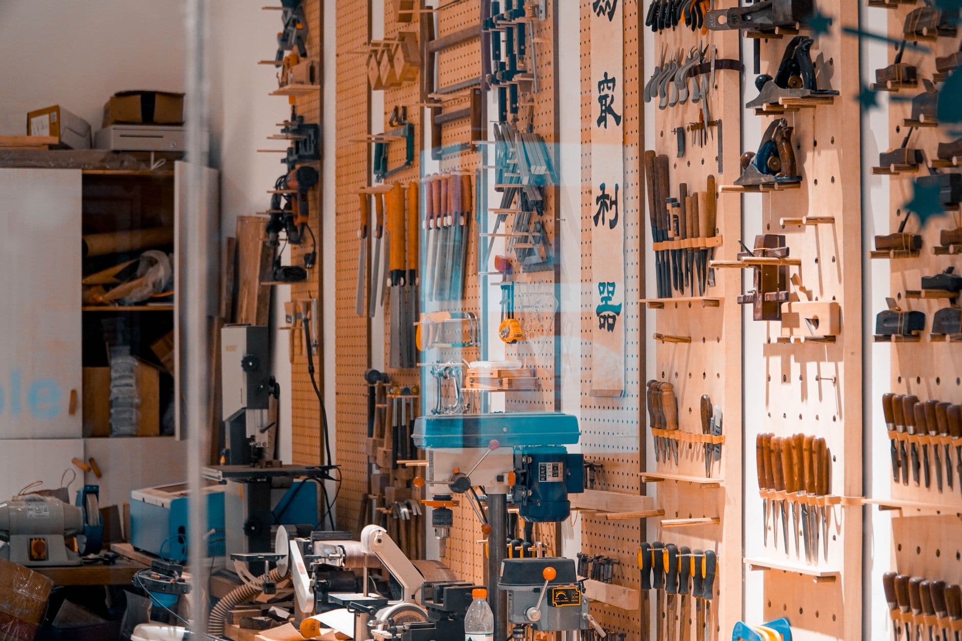 A workshop wall with hand tools hung in rows on wooden boards