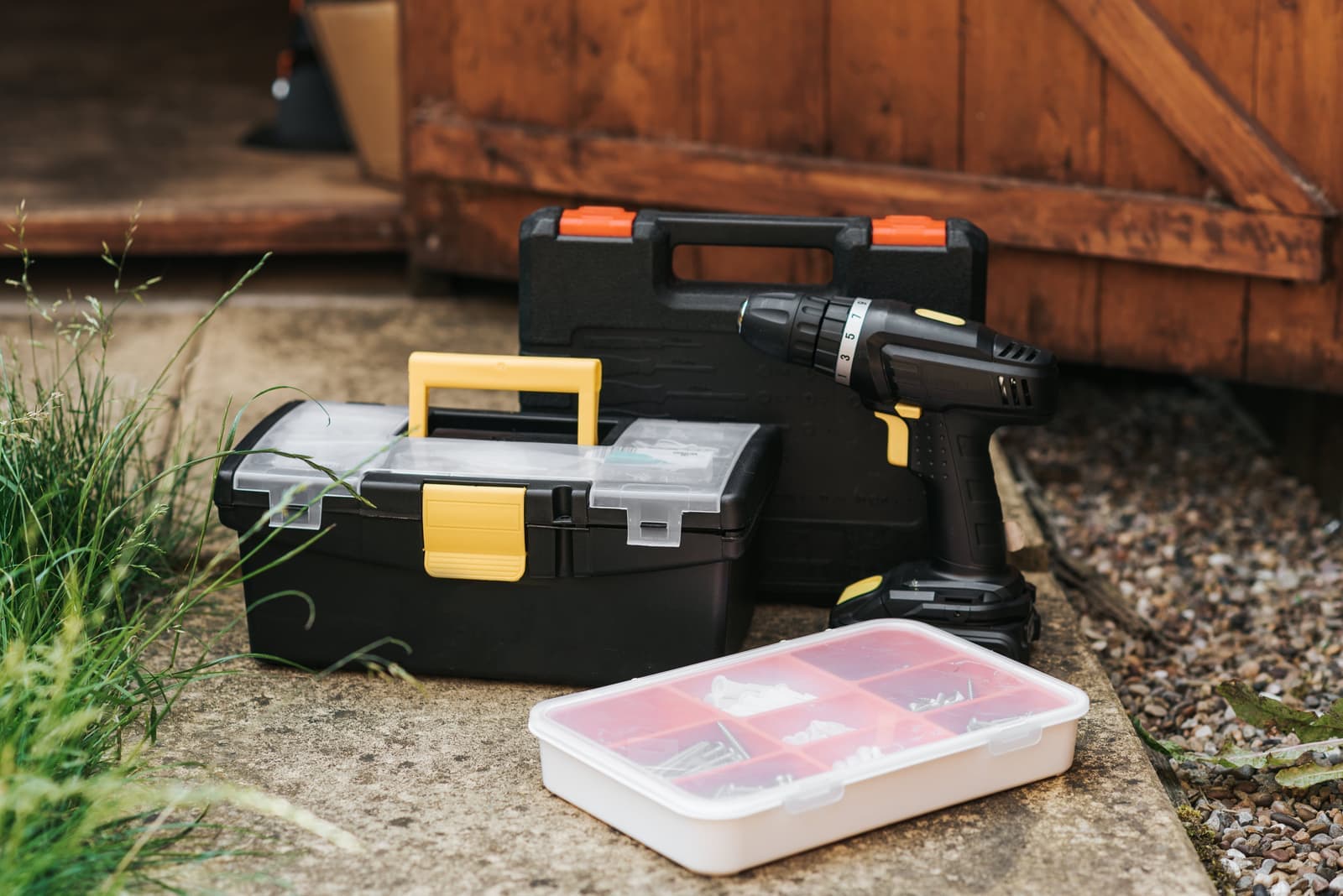 A cordless screwdriver in its case beside boxes at a garage entrance