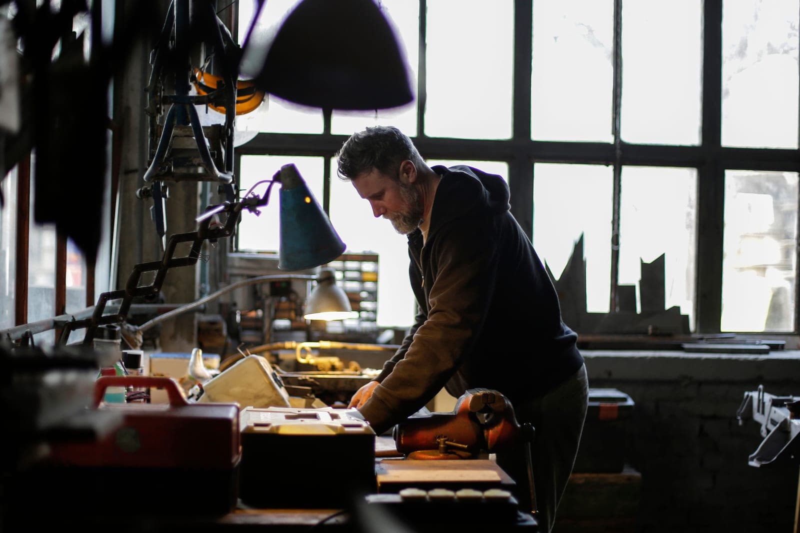 A mechanic standing at a workbench in a workshop, seen from the side