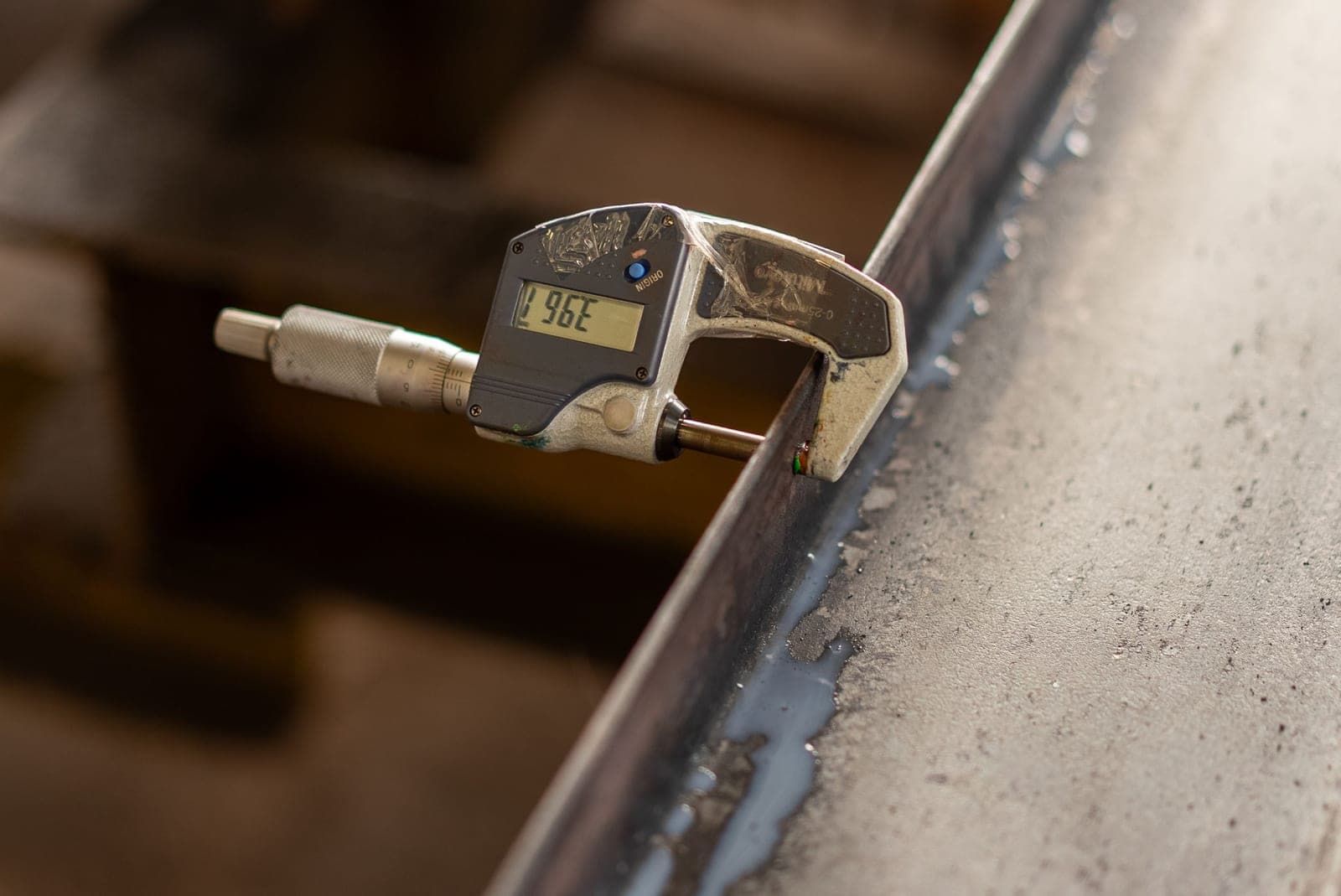A digital caliper measuring the thickness of a piece of metal