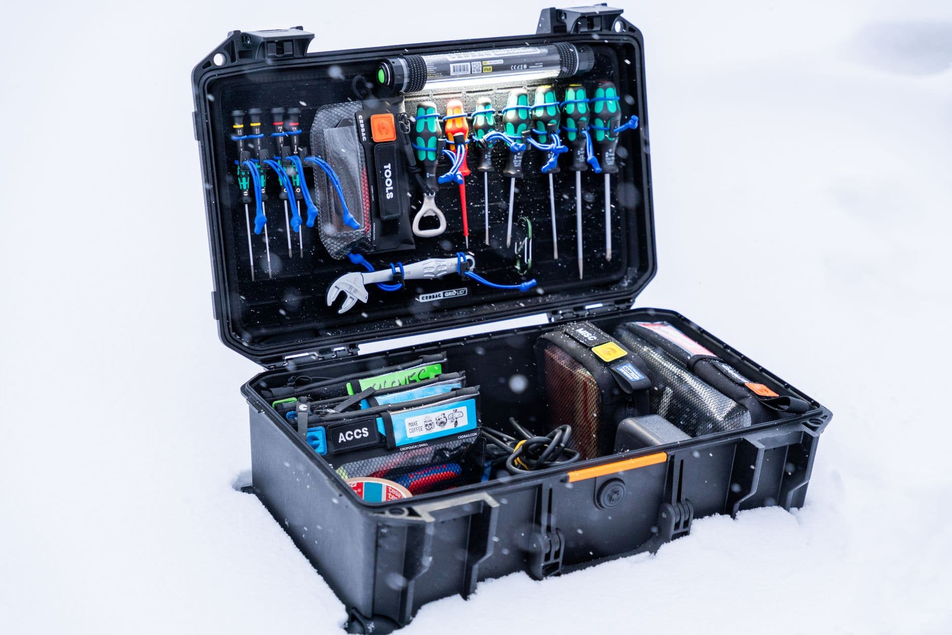 An open professional tool case filled with hand tools and equipment, photographed outdoors
