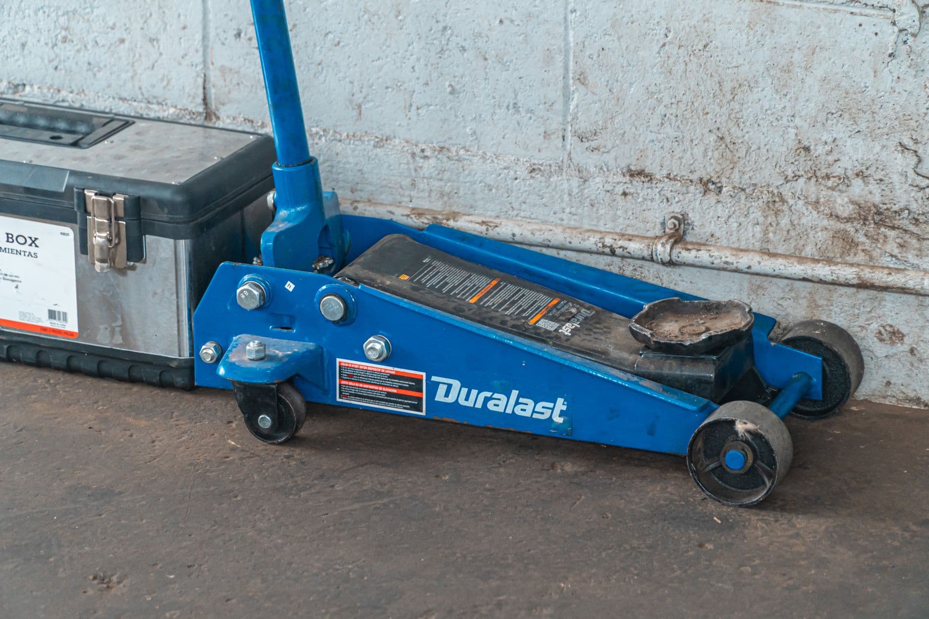 A blue hydraulic floor jack beside a toolbox in an automotive garage