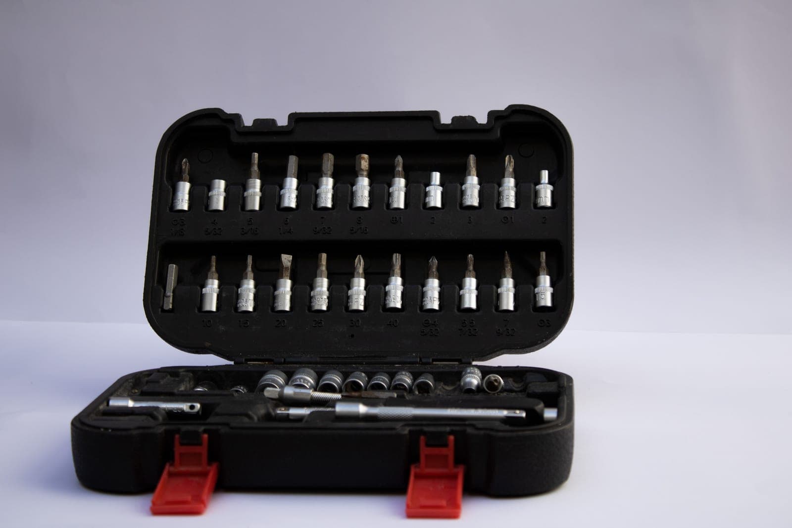 An open tool box holding screwdriver bits and assorted hand tools