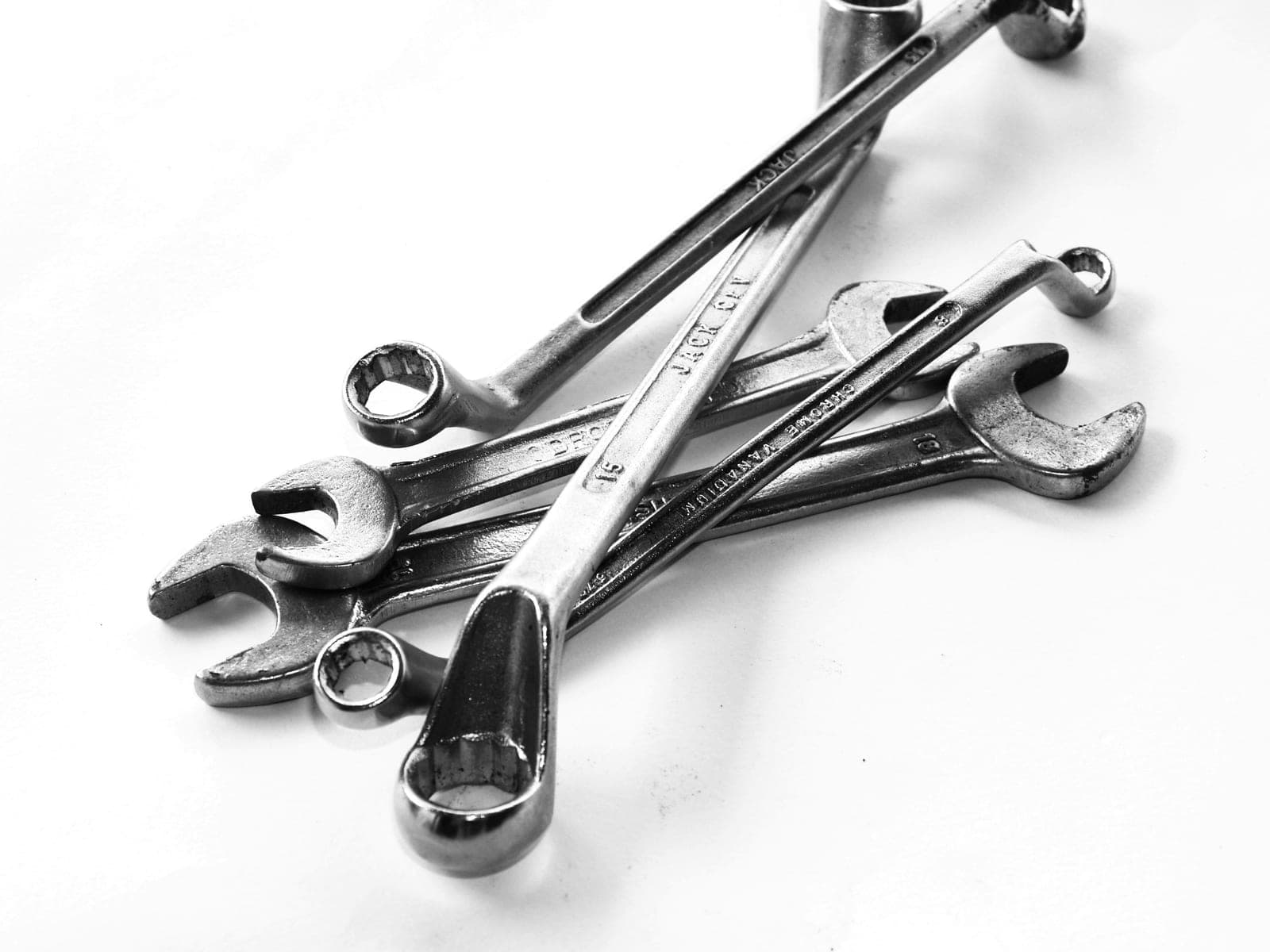 A set of steel wrenches arranged against a plain backdrop