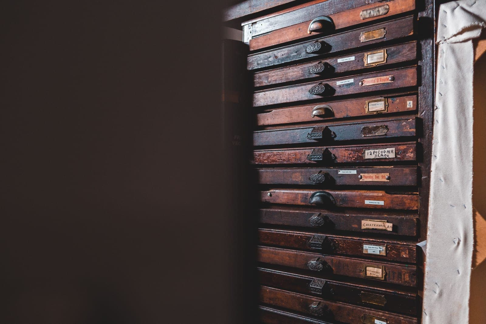 A tall wooden cabinet of many shallow labeled drawers