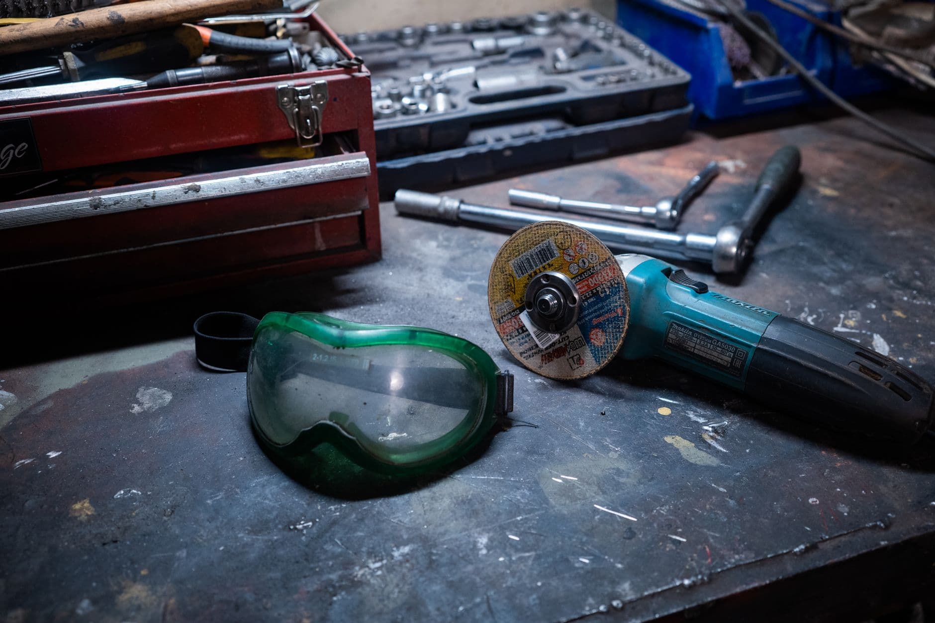 A workshop bench with a grinder, hand tools and safety goggles