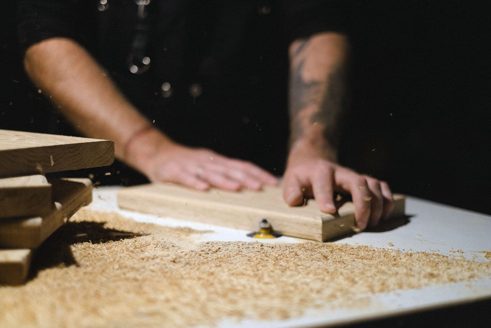A woodworker shaping a plank at a router table