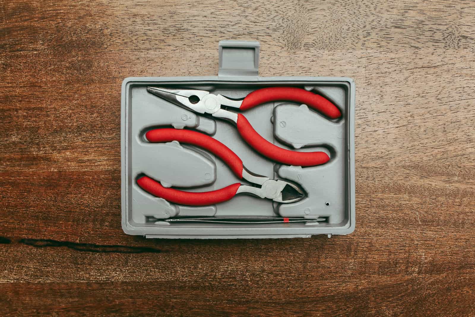 A set of red-handled pliers laid out in a portable tool case