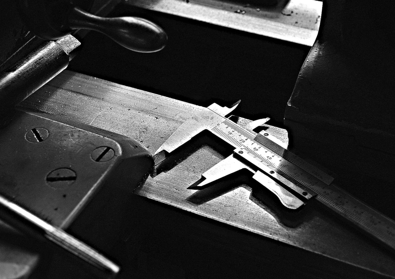 A caliper resting on a workshop table, photographed in black and white
